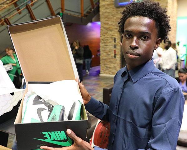 A young man poses for a photo with new shoes in a box